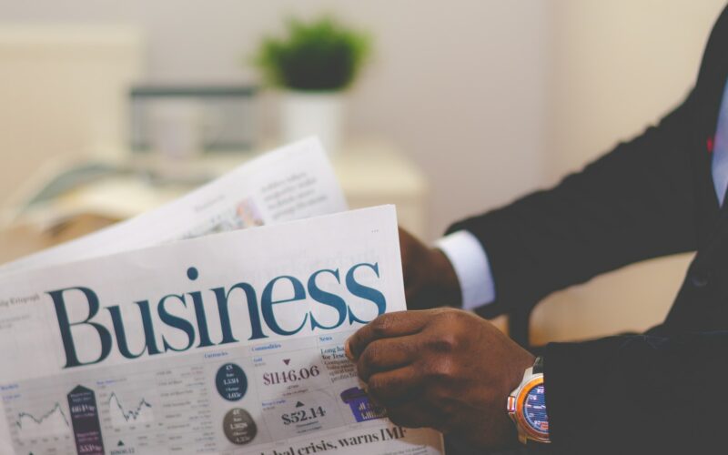 person wearing suit reading business newspaper