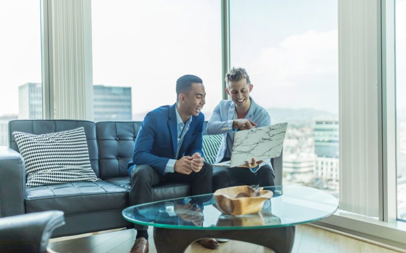 two men in suit sitting on sofa